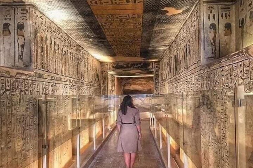 A corridor with hieroglyphs on the walls and a person walking down it. 1