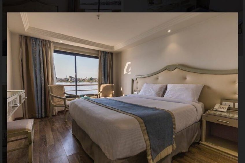 A hotel room with a large bed, a desk, and a view of a cityscape. 5