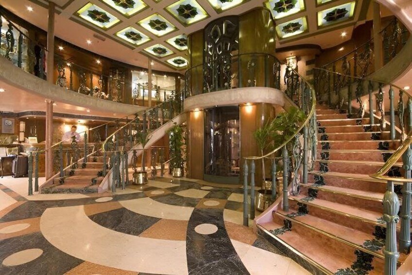 A grand interior with a marble floor, a curved staircase, and a large chandelier. 2