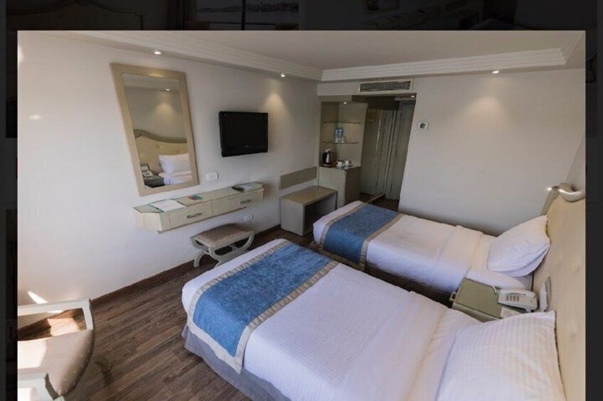 A hotel room with two beds, a desk, a chair, a TV, and a mirror. 4