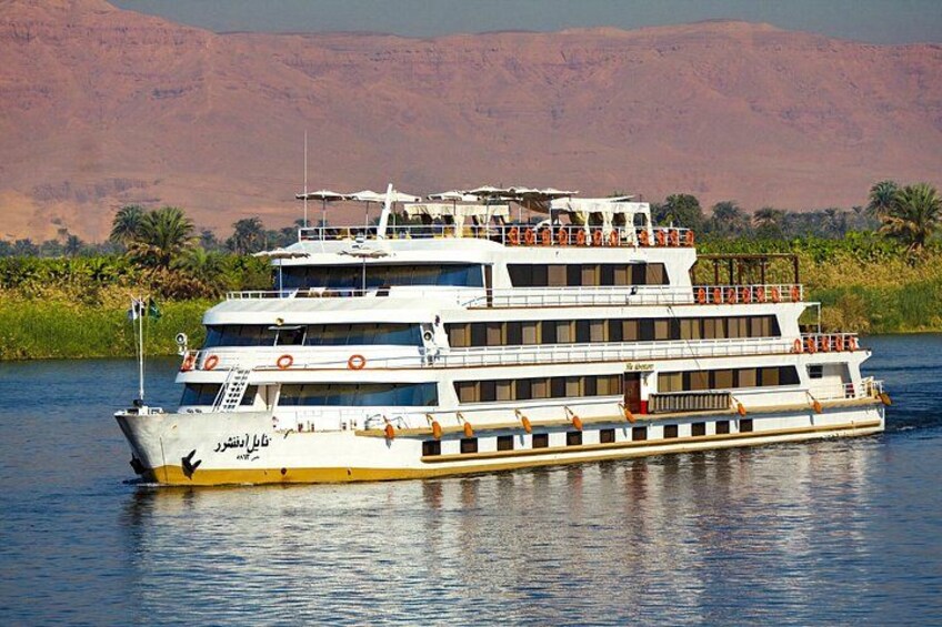 A large river cruise ship with multiple decks and a mountainous backdrop. 1