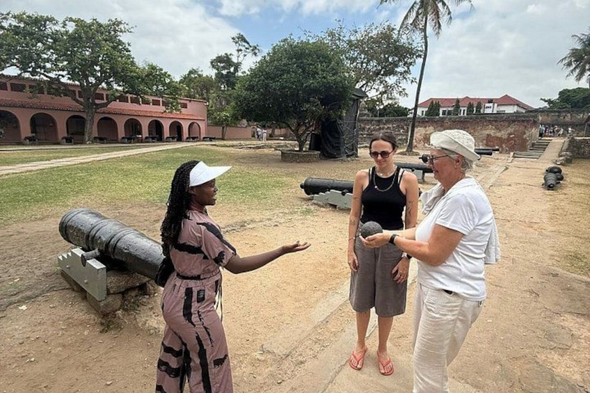 A historical site with cannons, a building with arches, and a clear sky. 3