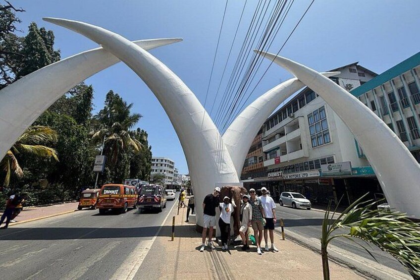 A street with a distinctive white arch structure, vehicles, and pedestrians. 2