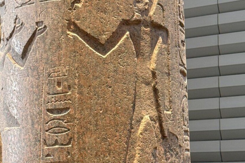 A stone with ancient carvings, including a figure and hieroglyphs. 5