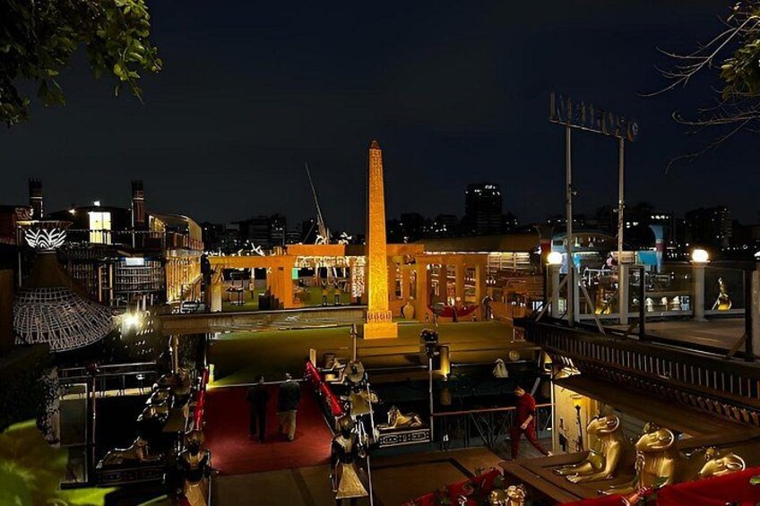 Een stadsbeeld 's nachts met verlichte gebouwen, een opvallende hoge constructie en een evenement met een rode loper. 4