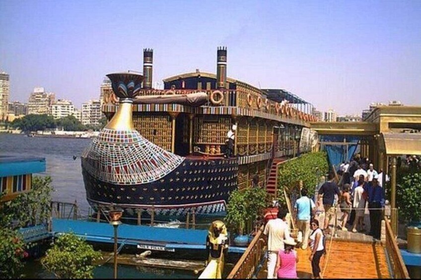 Een grote, versierde boot die aan een steiger is afgemeerd, met mensen die eromheen lopen. 3