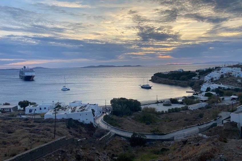 A coastal town with white buildings, a road, and boats on the water. 1