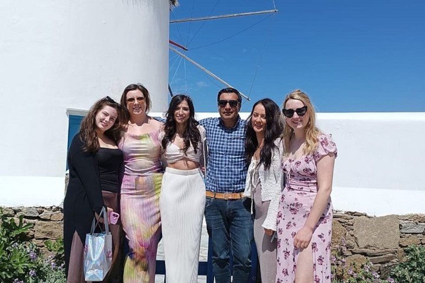 A group of people standing in front of a white building with a blue sky in the background. 2