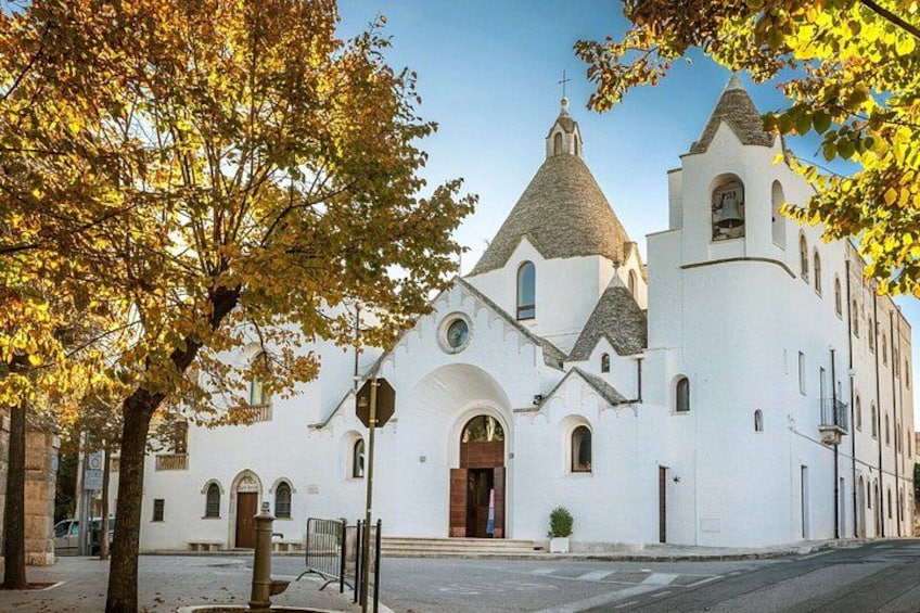 A white church with a bell tower, arched windows, and a tiled roof. 3