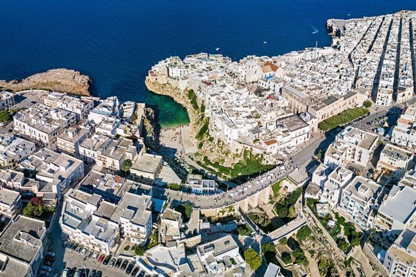 An aerial view of a coastal town with buildings, a coastline, and a clear sky. 1
