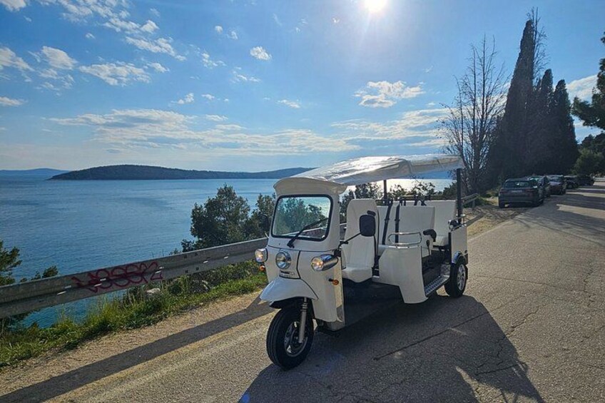 Un vehículo utilitario blanco estacionado en una carretera con una vista panorámica de un lago y colinas al fondo. 1