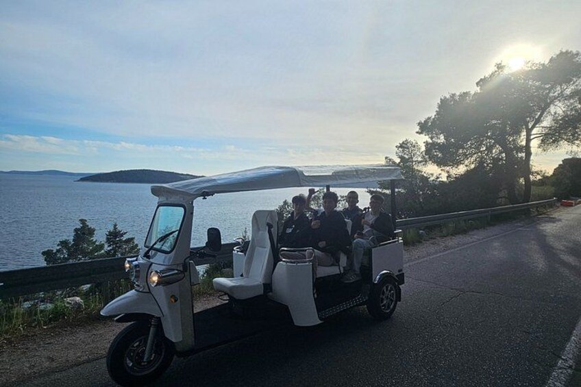Un carrito de golf blanco con pasajeros circulando por una carretera cerca del agua. 4