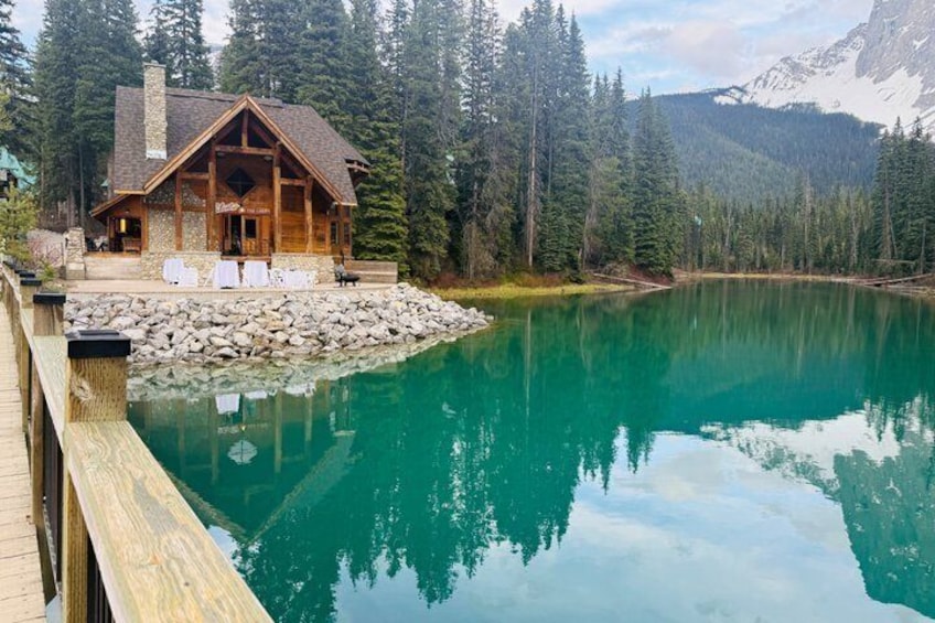 Una cabaña junto a un lago turquesa rodeada de bosque. 5