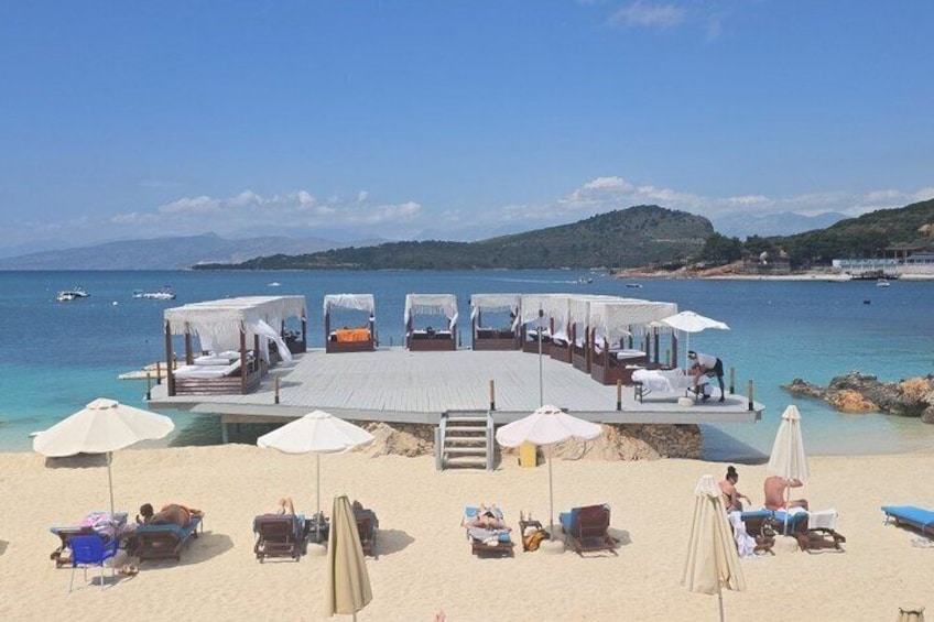 Un ristorante sulla spiaggia con posti a sedere all'aperto, un pontile in legno e ombrelloni. 2