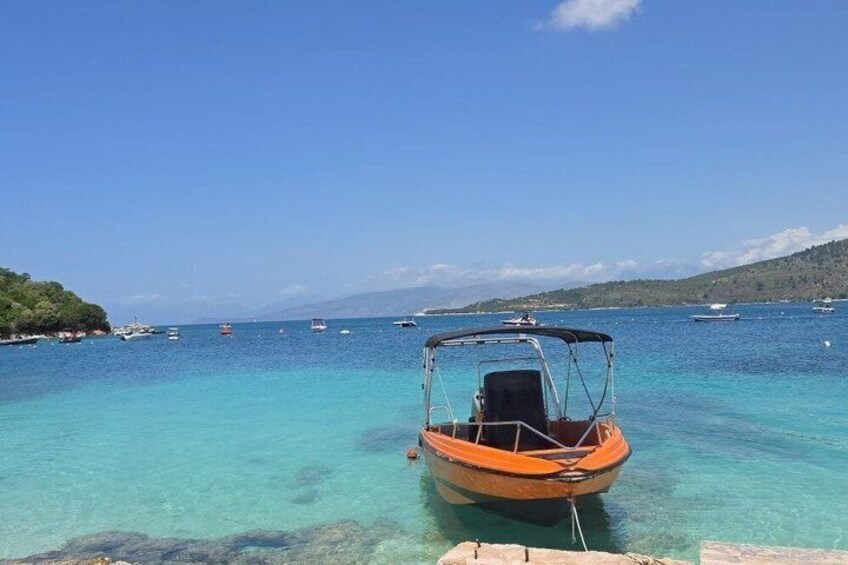 Mare blu intenso con una piccola barca arancione ormeggiata al molo. 5