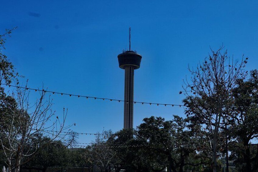 A tall tower with a spherical observation deck, surrounded by trees and a clear blue sky. 4