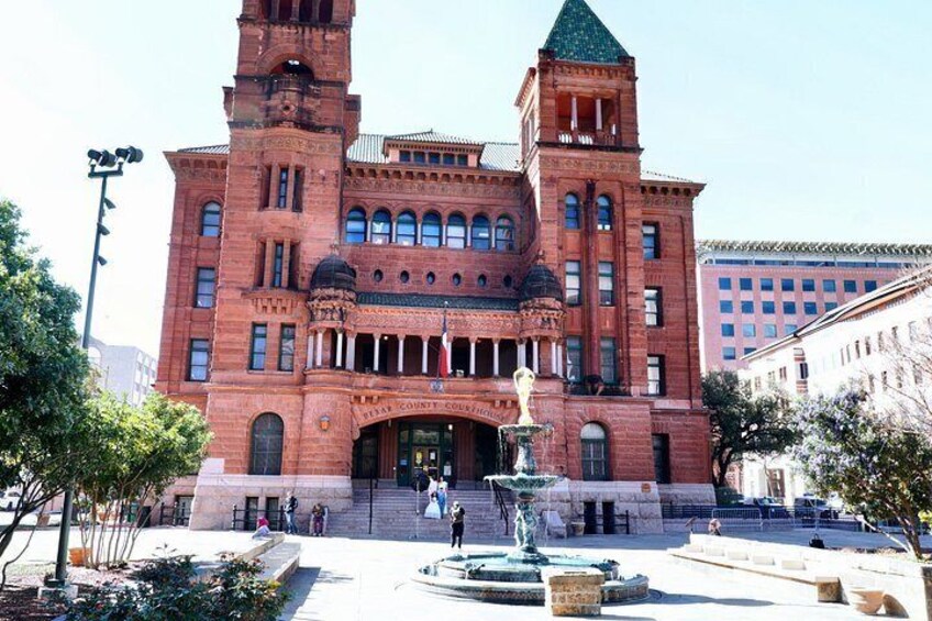A large red brick building with a tower, a fountain, and a statue in front. 5