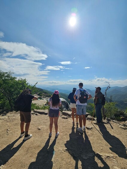 A group of hikers on a dirt path with a clear sky and mountains in the background. 4