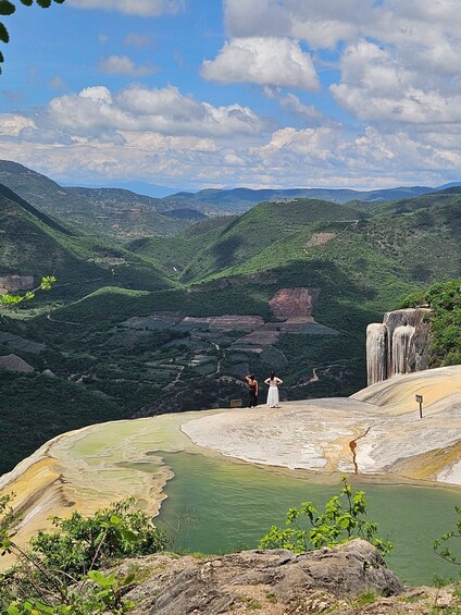 A landscape with a valley, green hills, a body of water, and a waterfall. 5