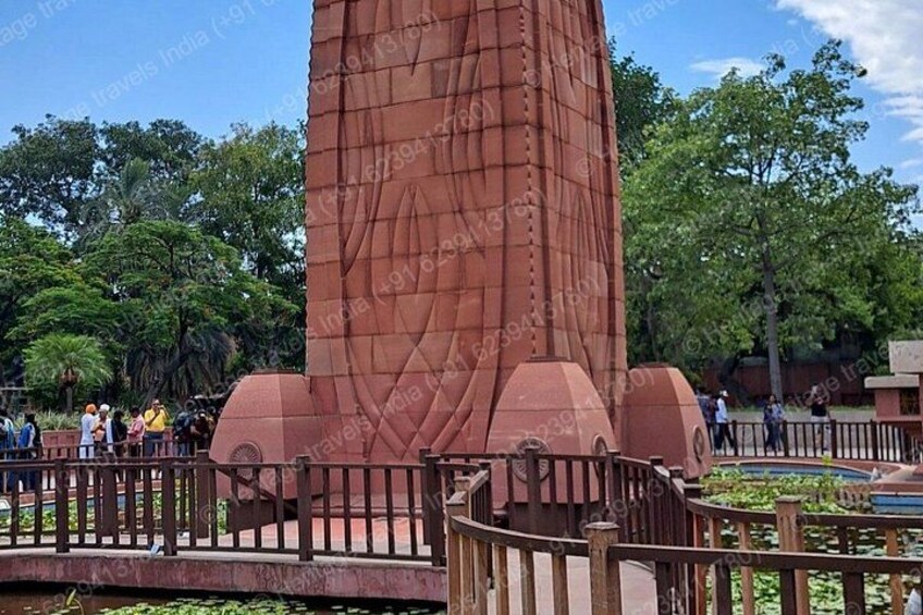 Un grande monumento rosso con decorazioni elaborate, circondato da una recinzione in legno e uno stagno con ninfee. 3