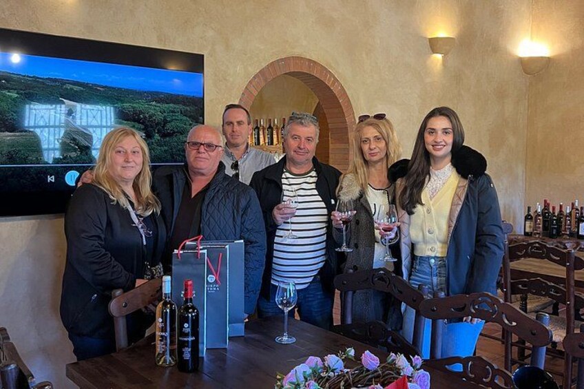 Un grupo de personas en una degustación de vinos, con botellas y copas sobre la mesa. 1