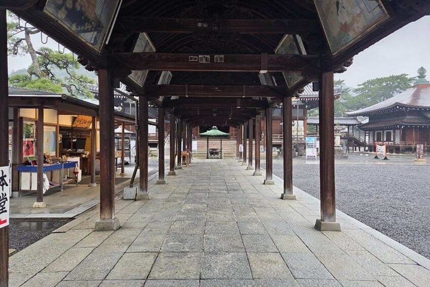 A traditional Japanese covered walkway with stone flooring and wooden pillars. 2