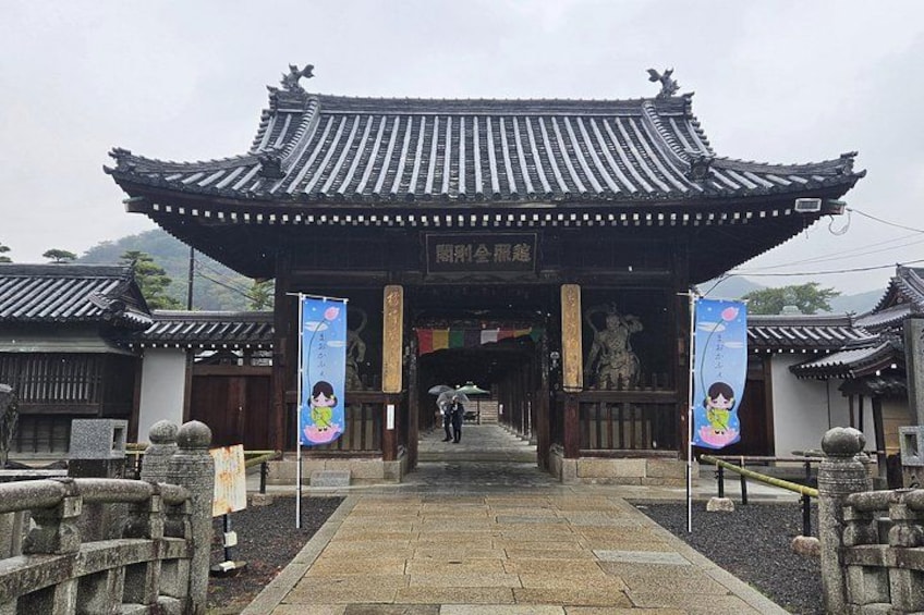 A traditional gate with a tiled roof, stone pillars, and banners. 3