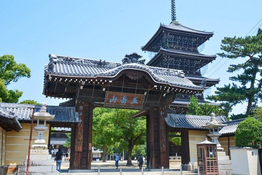 A traditional Japanese gate with multiple tiers and a signboard. 1