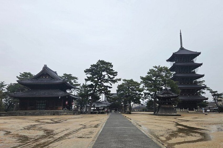 A traditional Japanese temple with a central pathway, surrounded by trees and a large pagoda. 4