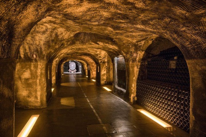 Un tunnel souterrain doté de voûtes en arc, d’une allée centrale et d’un mur orné de motifs sur l’un des côtés. 3