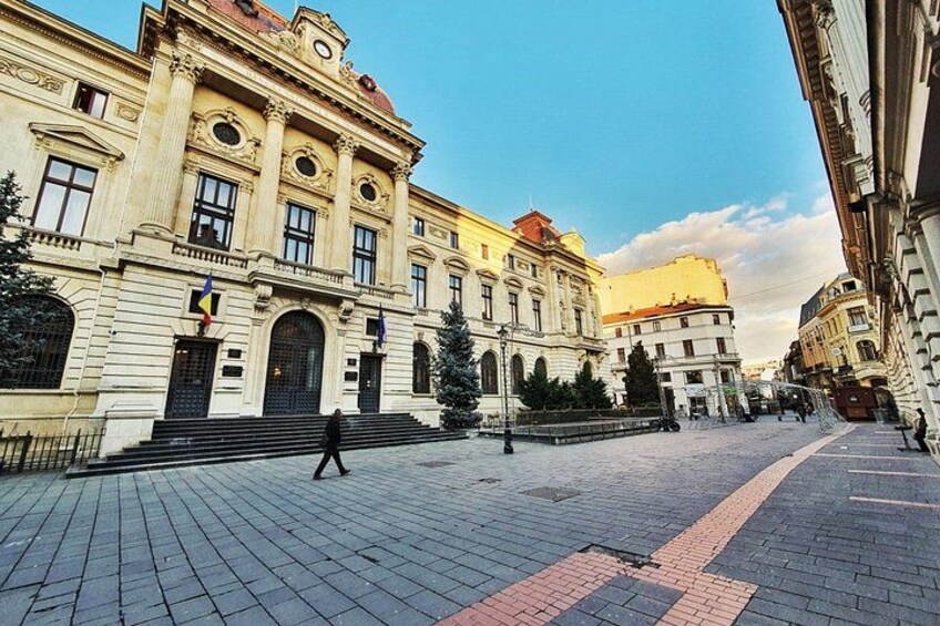 Una piazza lastricata con architettura classica, una persona che cammina e cielo sereno. 3