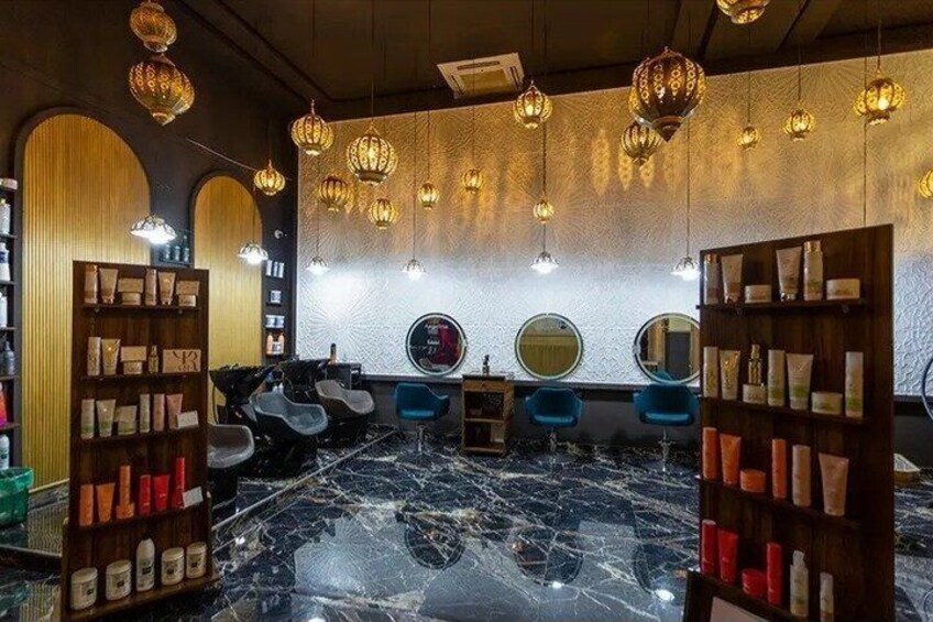 A salon with marble floors, blue chairs, and shelves of hair products. 4