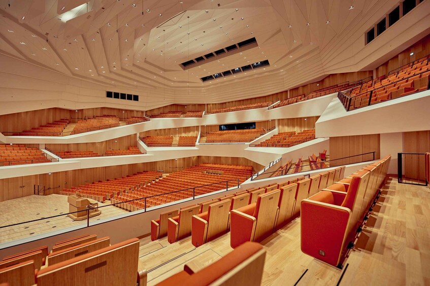 A multi-level auditorium with tiered seating and a wooden interior. 1