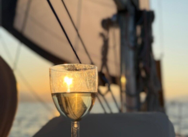 A glass of white wine on a table with a blurred background of a sailboat. 1