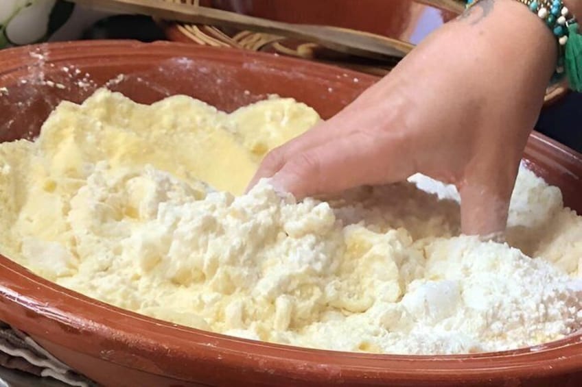 Een hand mengt bloem en boter in een kom. 1