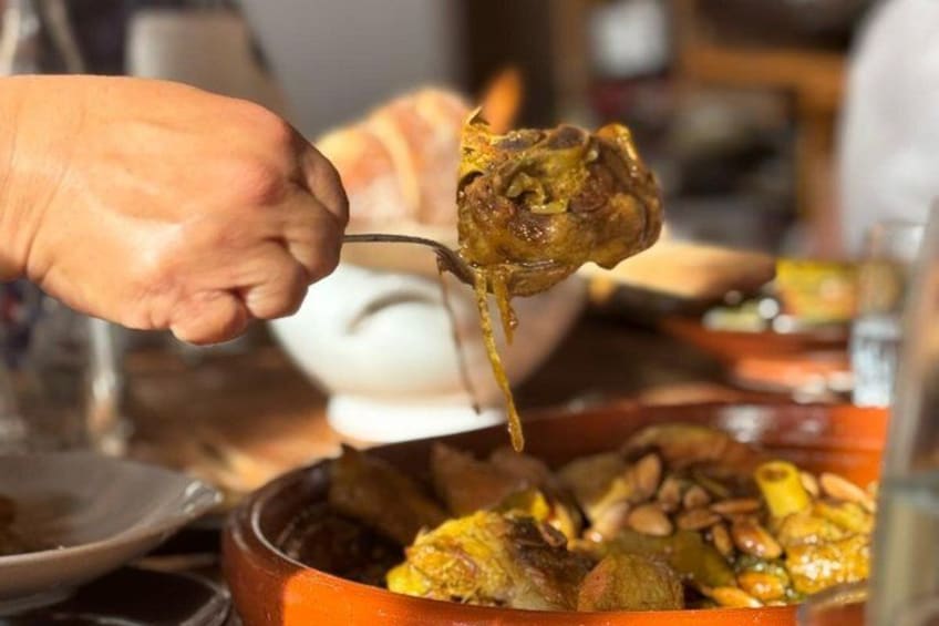 Una mano sosteniendo un trozo de comida, probablemente carne, que se sirve de una olla. 4