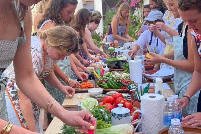 Personas preparando comida al aire libre con verduras y utensilios de cocina. 1