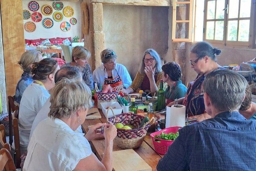 Un grupo de personas sentadas alrededor de una mesa con comida y bebidas, en un ambiente rústico con paredes de madera y una ventana. 2