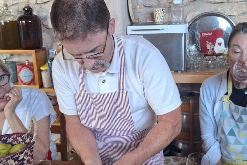 Una persona con delantal a rayas trabajando en la encimera de una cocina, con diversos utensilios y un microondas al fondo. 3