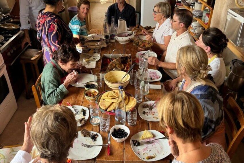 Un grupo de personas cenando en una mesa de madera con diversos platos y bebidas. 5