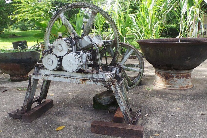 An old, rusted mechanical device with wheels and gears, placed outdoors on a concrete surface. 3