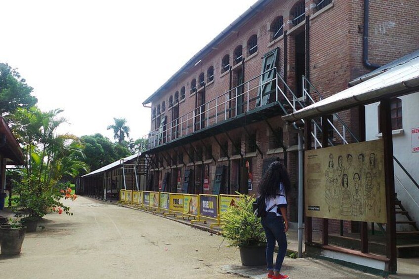 A brick building with a staircase, a person standing, and a poster with text. 4