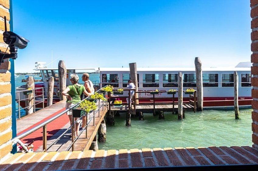 A dock with people, a boat, and a brick wall. 3