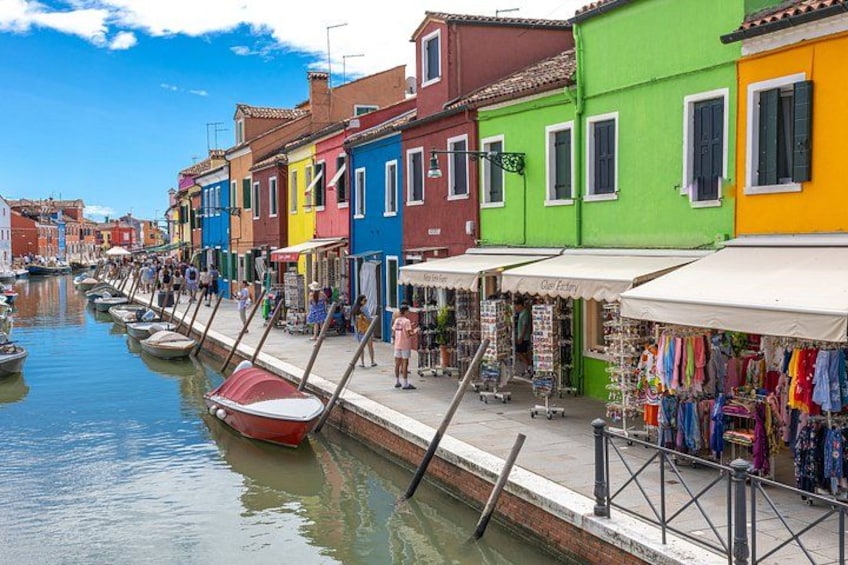 A canal with colorful buildings, boats, and people walking along the waterfront. 5