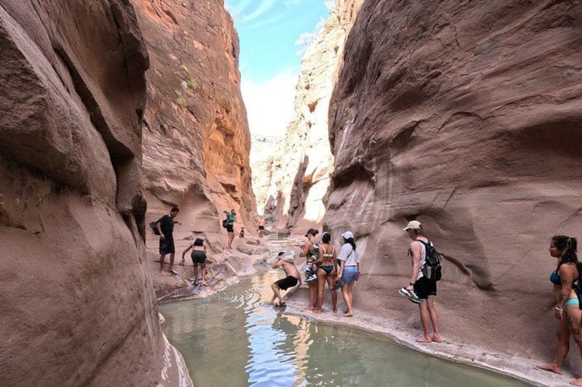 Un gruppo di persone in piedi vicino a una piscina in un canyon. 1