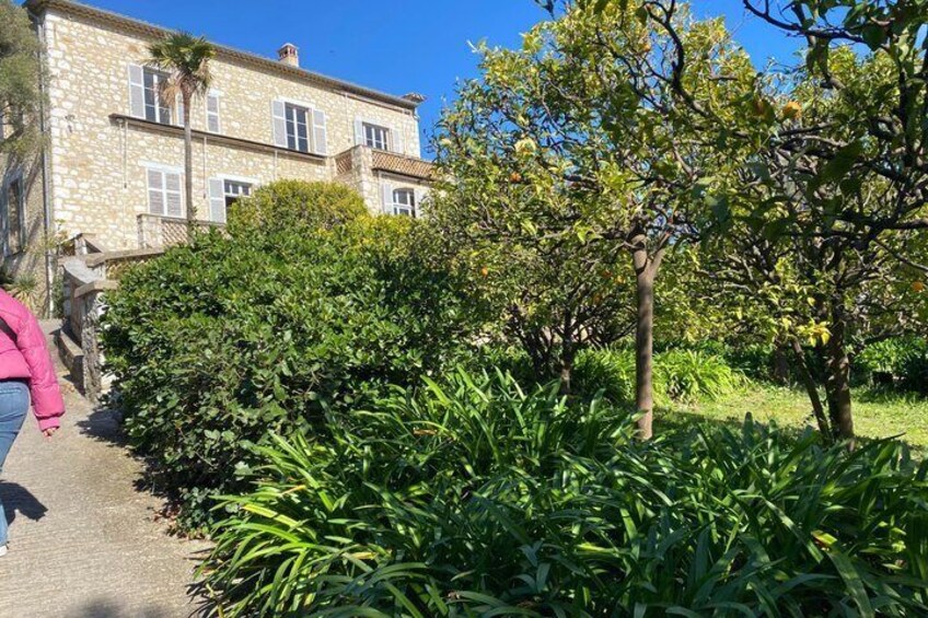 A stone building with a garden and trees. 3