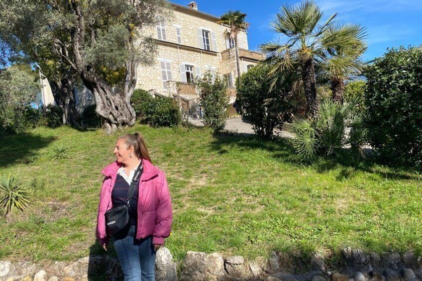 A person standing in a grassy area with a large tree and a building in the background. 4