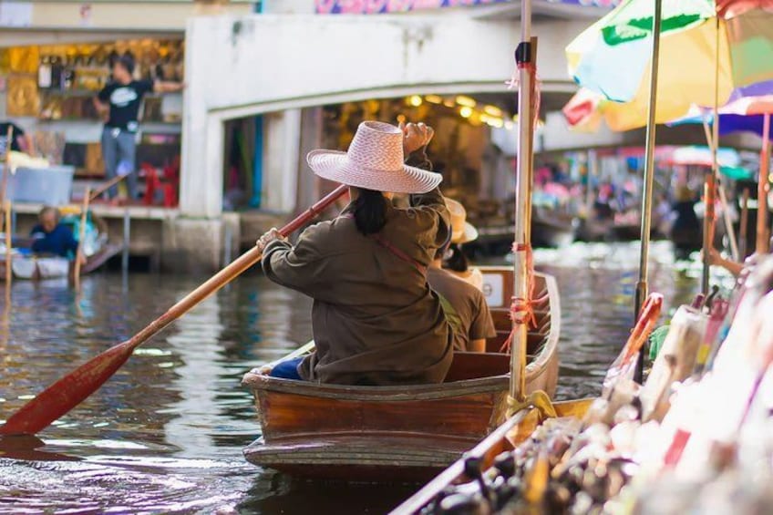 A person in a boat using a long paddle, surrounded by water and other boats. 3