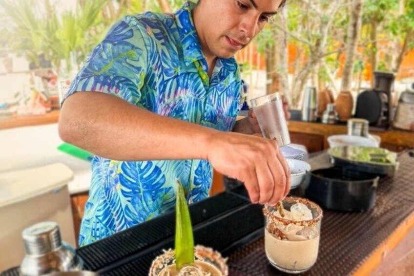 Une personne prépare une boisson et la décore avec une feuille tropicale. 3