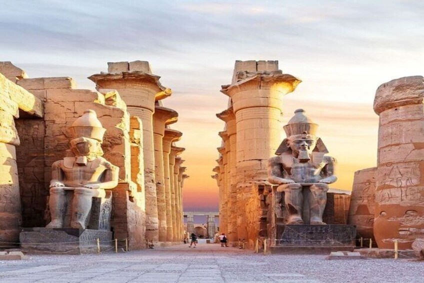 Ägyptische Säulen aus der Antike mit Statuen vor einem Sonnenuntergangshimmel. 1